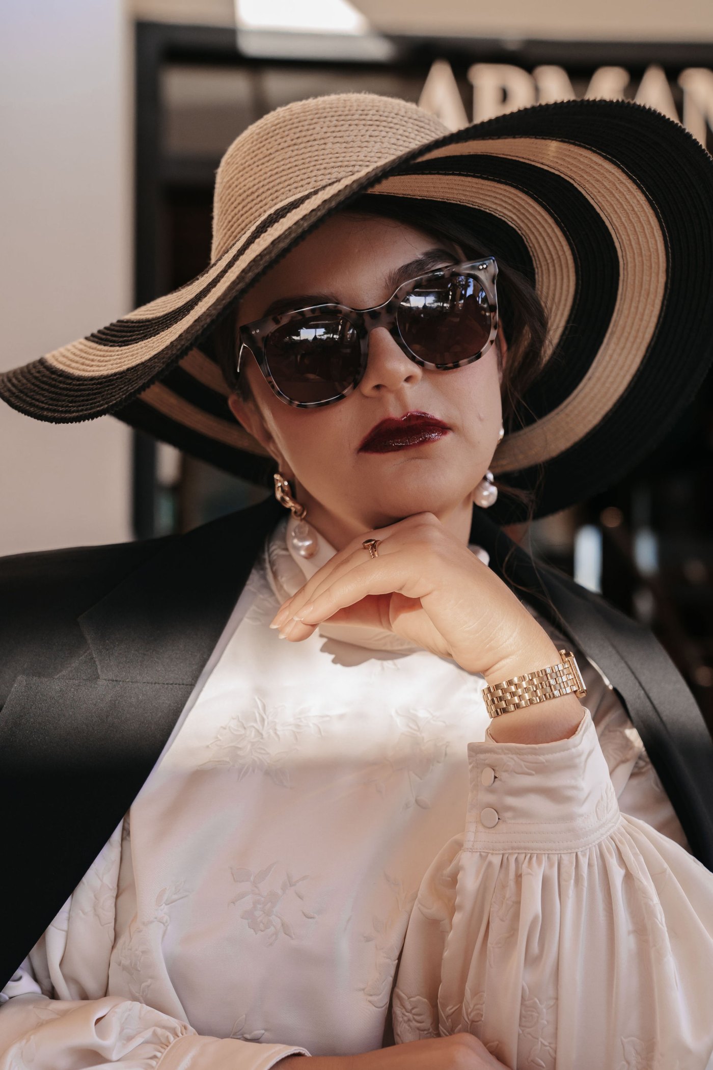 Editorial Cannes · gestreifter Hut und weiße Bluse vor dem Armani Caffè