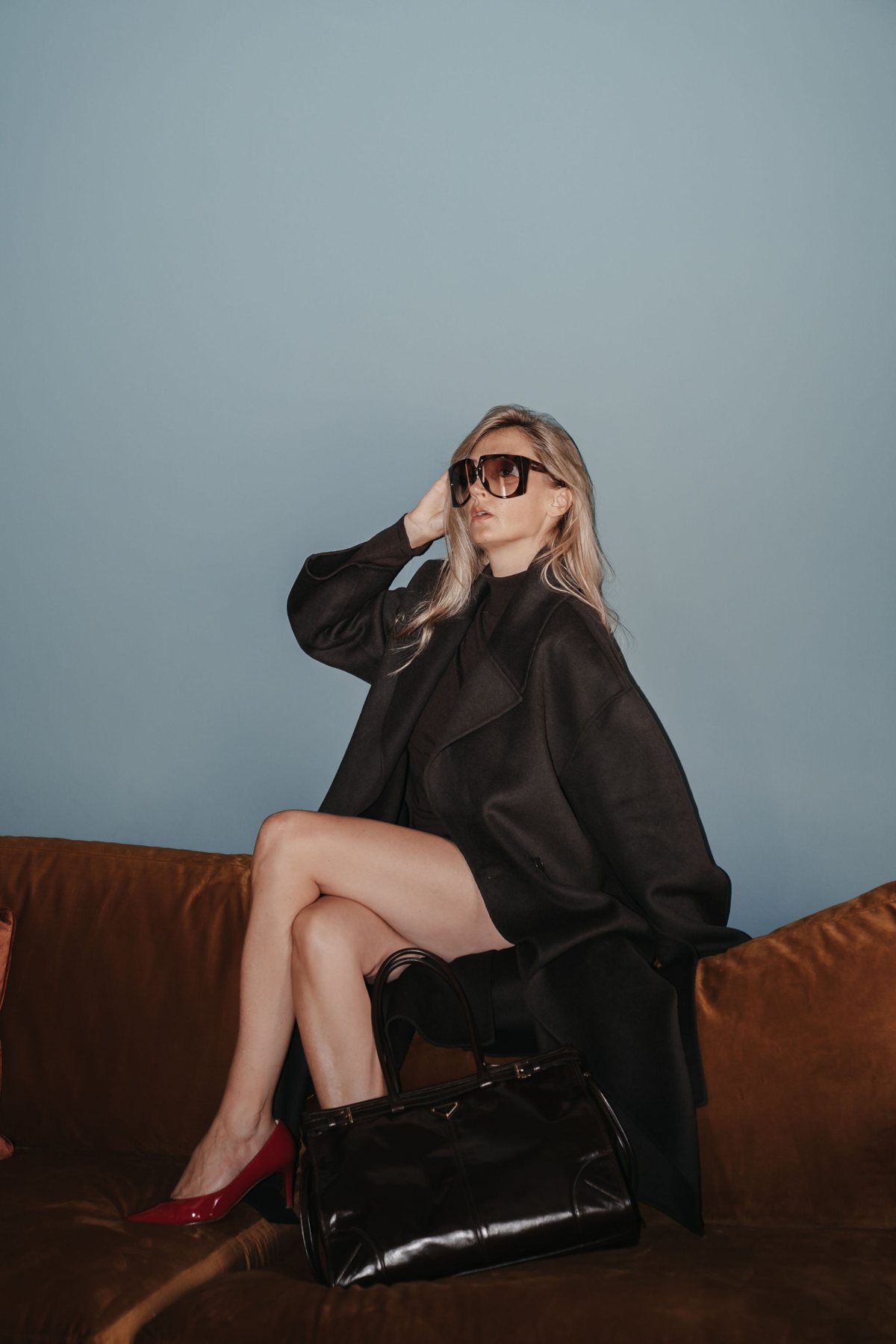 Daniela Vanzetta im schwarzen Mantel auf dem Cognac-Sofa, Personal Branding Editorial auf Sylt