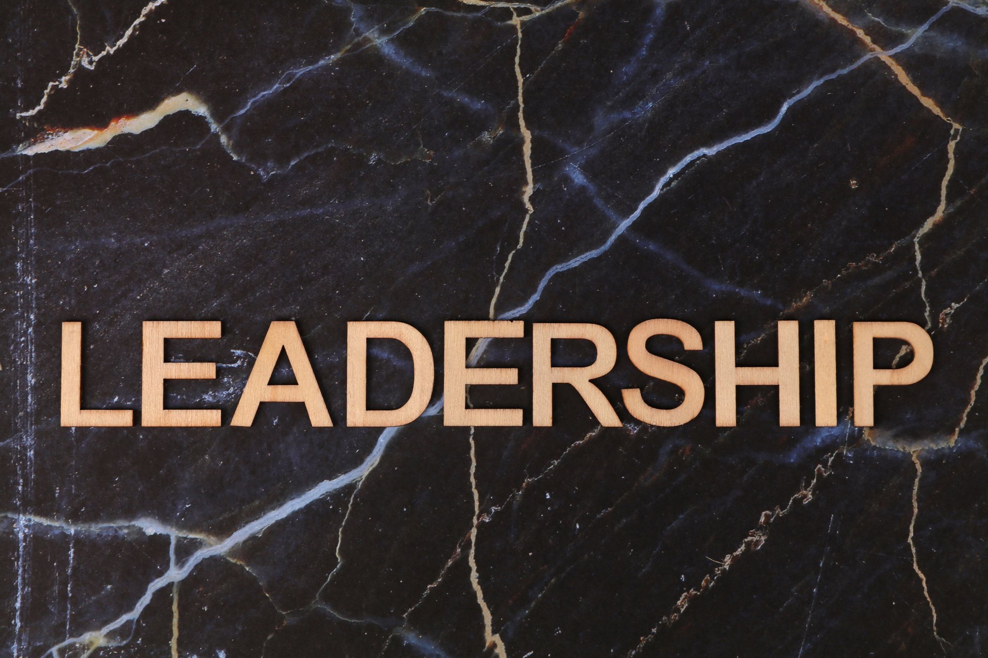 Der Schriftzug LEADERSHIP in Holzbuchstaben auf dunklem Marmor