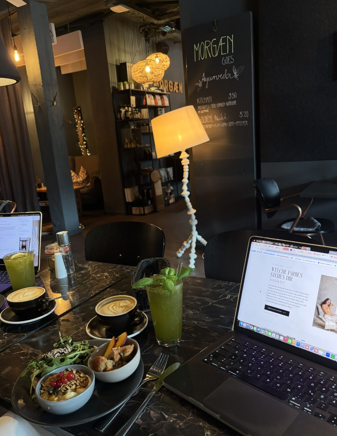 Laptop mit der Website von Sarah Bakker auf einem Caf&eacute;tisch, daneben Fr&uuml;hst&uuml;ck