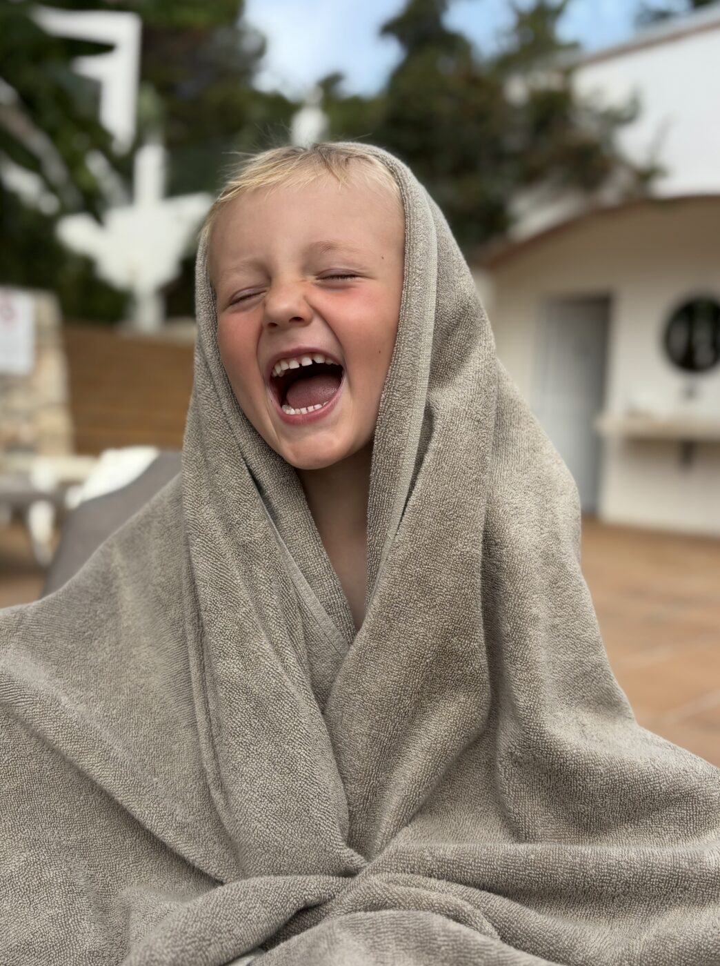 Lachendes Kind im Handtuch nach dem Schwimmen auf Mallorca